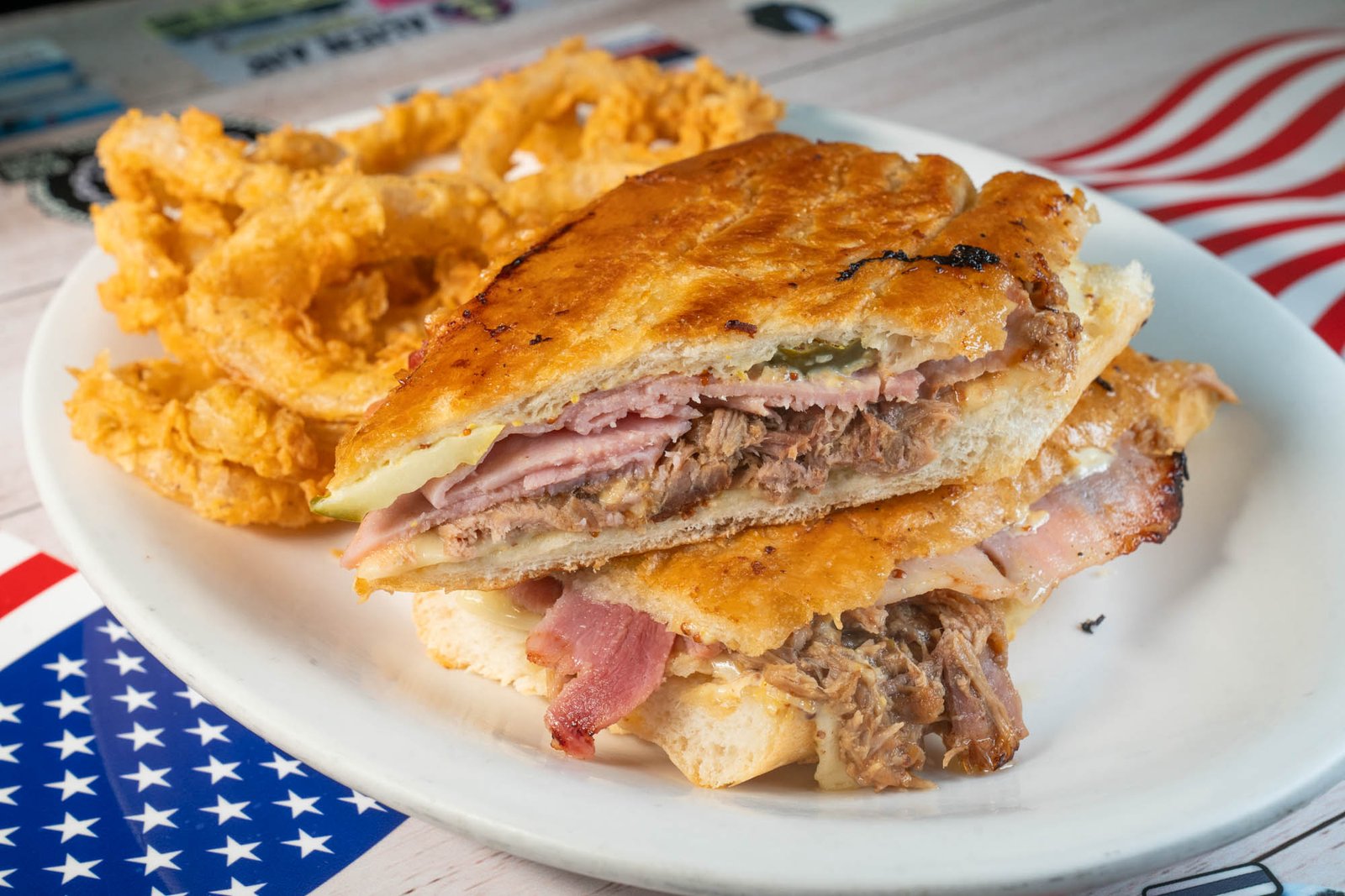 Pressed Cuban sandwich served with crispy onion rings
